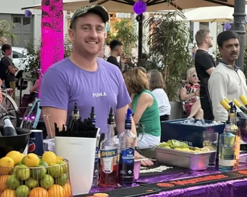 Getränkestand mit Barkeeper, Flaschen und frischen Früchten