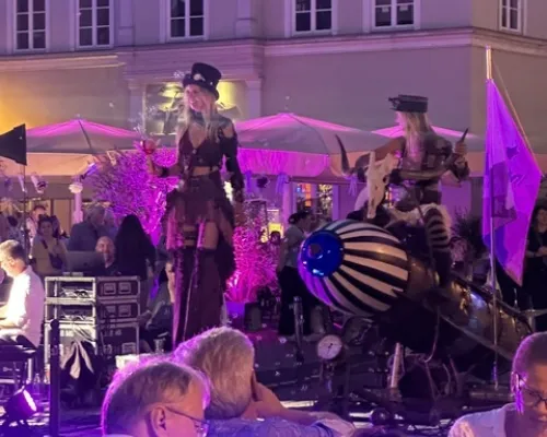 Abendliche Straßenmusik mit Publikum und violetter Beleuchtung