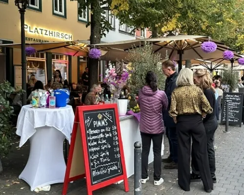 Restaurantaußenbereich mit Tafel, Stehtisch und Gästen