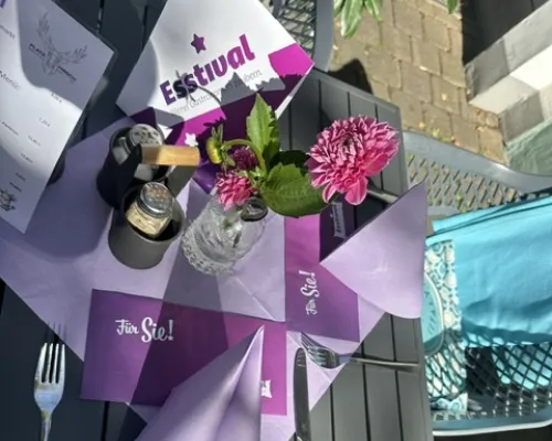 Gedeckter Tisch mit Esstival-Karte, Servietten und Blume